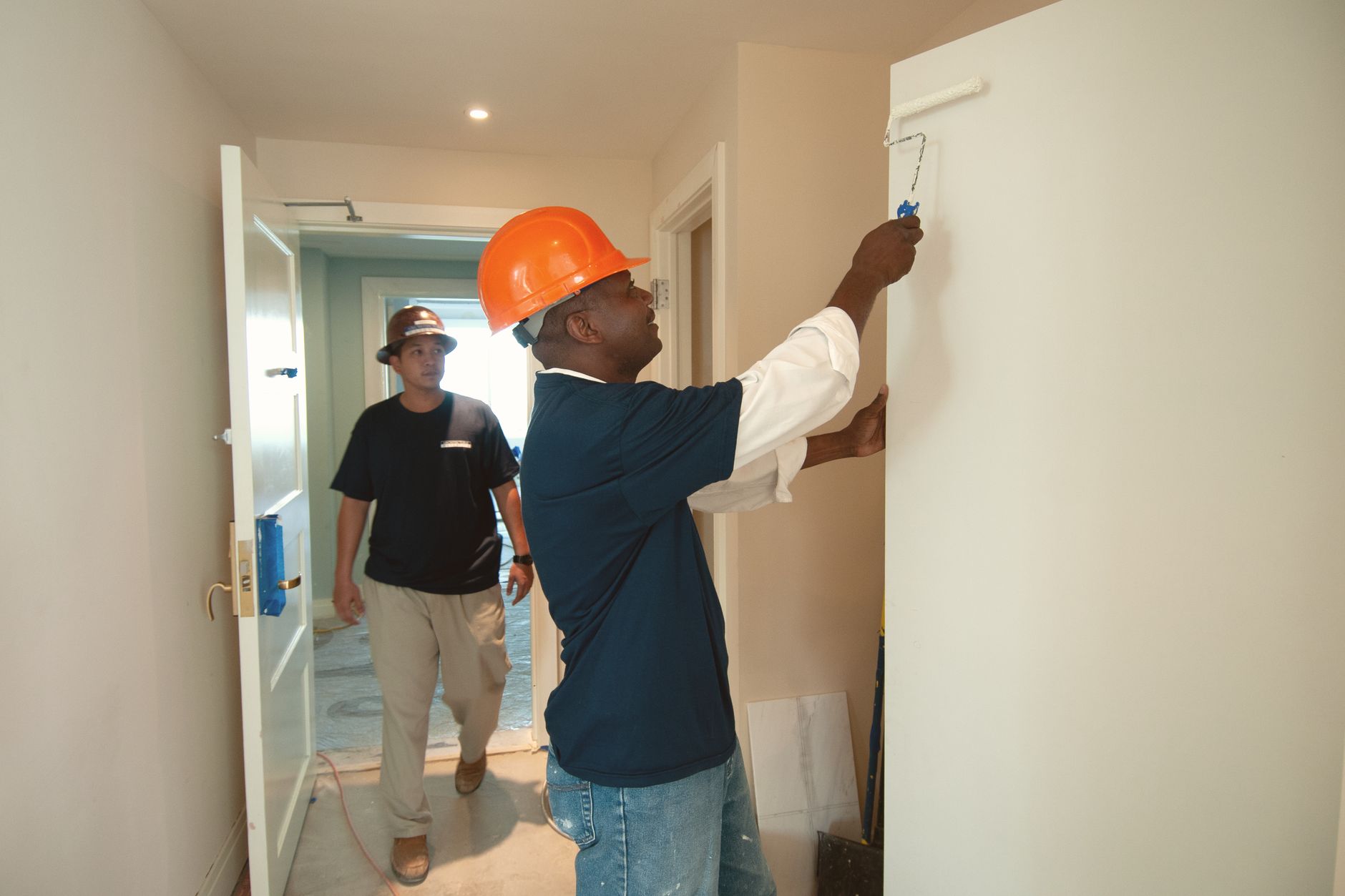 Two tradespeople at work in a hallway