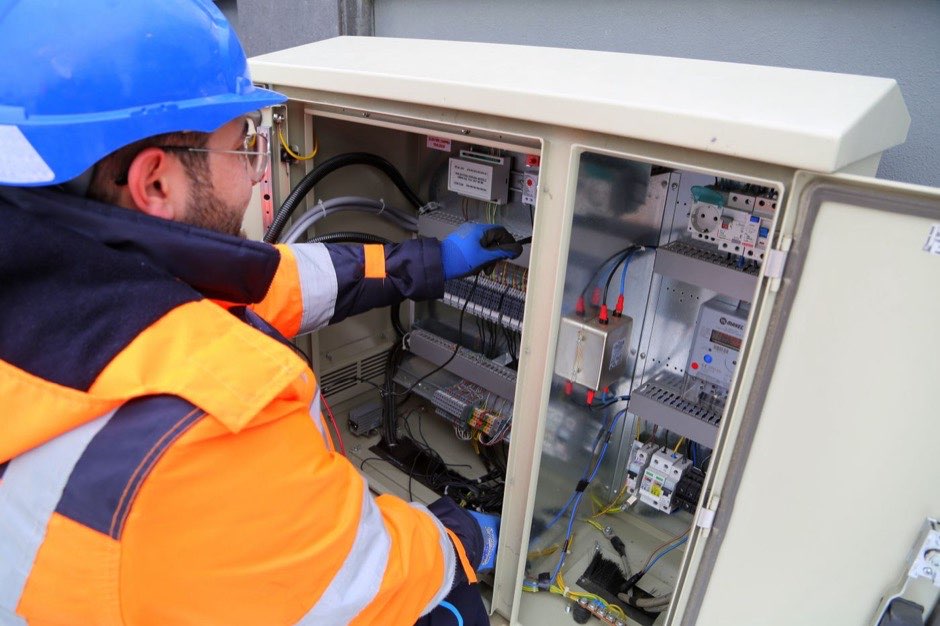 Electrician in hi-vis wiring a distribution board