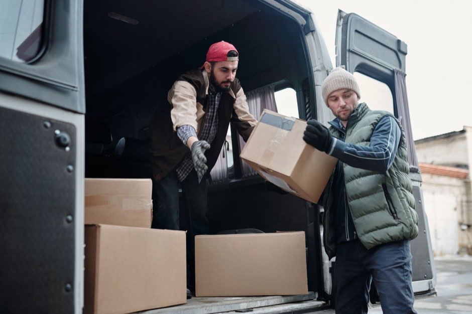 Two removals workers unloading boxes from a van